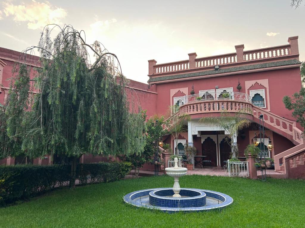 una grande casa rosa con una fontana nel cortile di Villa DALIA Route Ourika en Exclusivité a El Jemʼa Ghemat