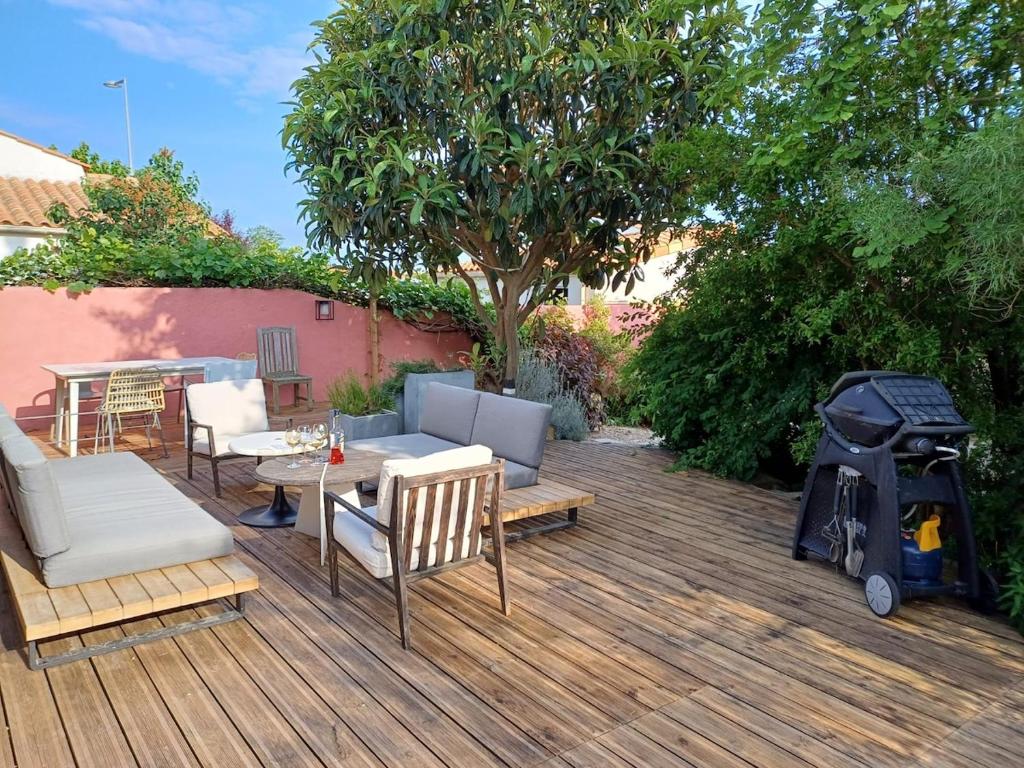 une terrasse en bois avec des chaises et un grill. dans l'établissement Quiet house with wooded garden, à Les Sables-dʼOlonne