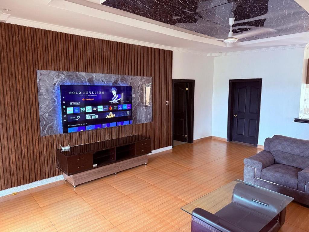 a living room with a couch and a large screen television at Palm Haven Villa in Kigali