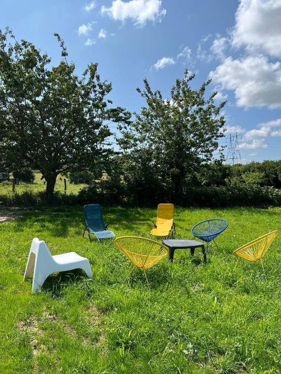 un groupe de chaises et de tables dans l'herbe dans l'établissement Gite Mont Saint Michel Chez Pépé Lucien, à La Gohannière