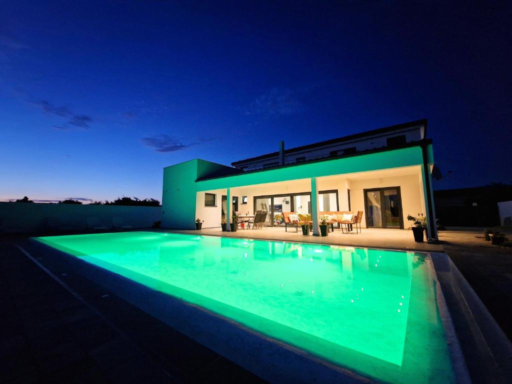a swimming pool in front of a house at night at Luxury Villa Triton in Novalja