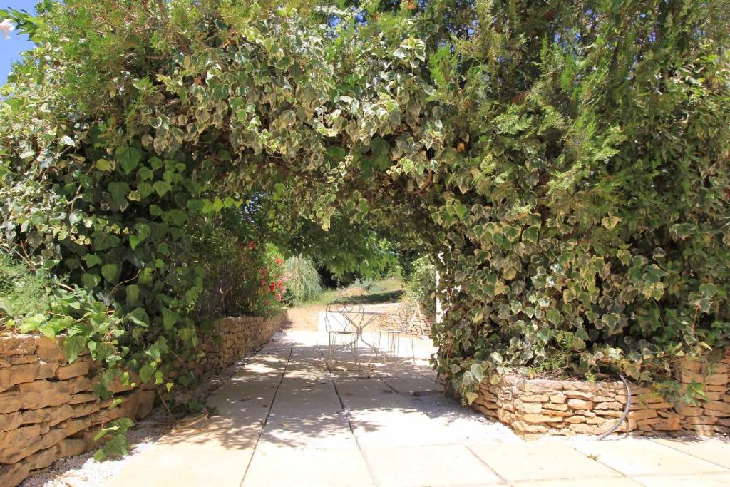 une arche de plantes avec un mur de pierre dans l'établissement Superbe rez de jardin avec aperçu mer et parking, à La Cadière-dʼAzur