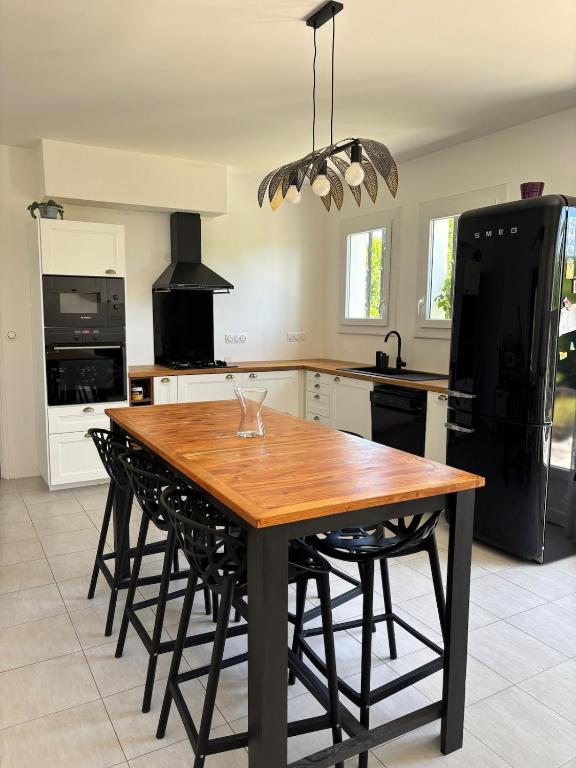 - une cuisine avec une table en bois et un réfrigérateur noir dans l'établissement Maison 3 chambres avec jardin, à Eymet