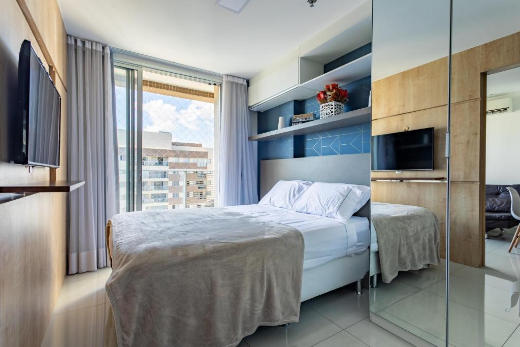 a bedroom with a bed and a tv and a window at Lindo e Aconchegante Apartamento no Shopping in Águas Claras