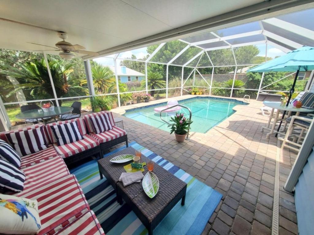 a patio with a couch and a table next to a pool at Beach Blossum home in Saint Augustine