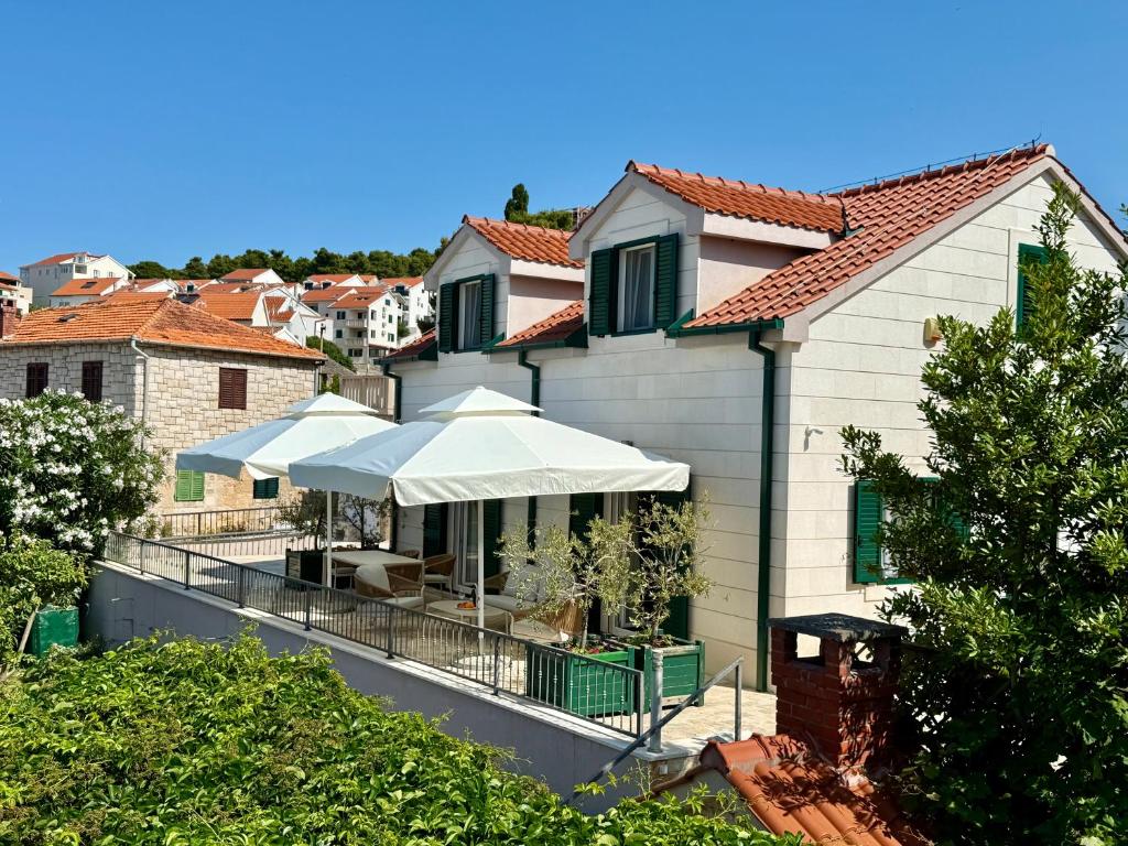 a house with an outdoor patio with an umbrella at House Bianca Brac - New Listing - Experienced host in Postira