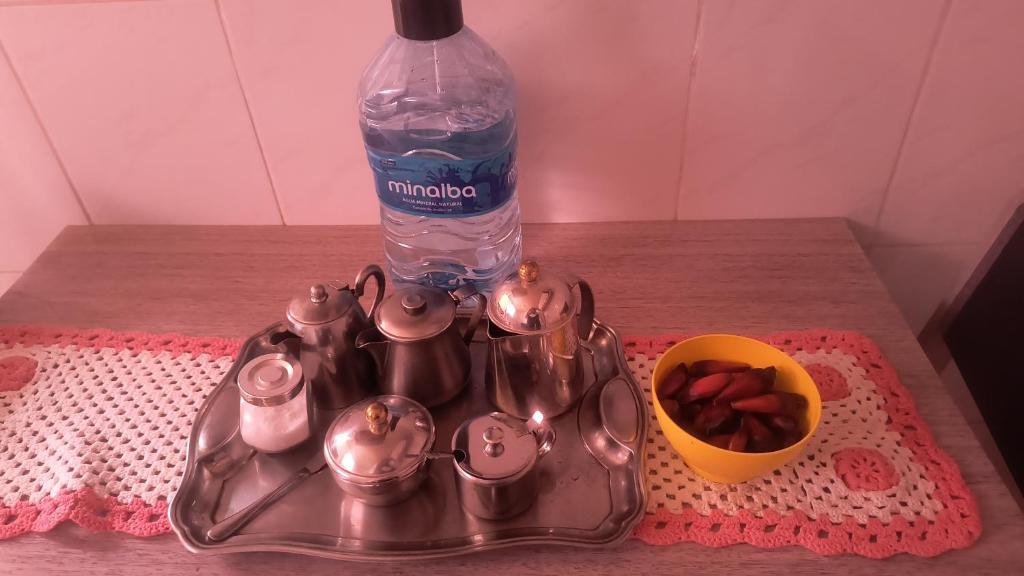 a tea set with a bottle of water and a bowl of strawberries at Flores da vovó in Campos do Jordão