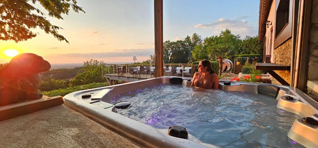 a woman sitting in a hot tub on a patio at Chambres d'hôtes Le Repère des Anges et SPA in Larnod