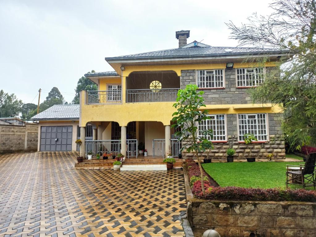 a large yellow house with a brick driveway at Kericho Finest Home in Kericho