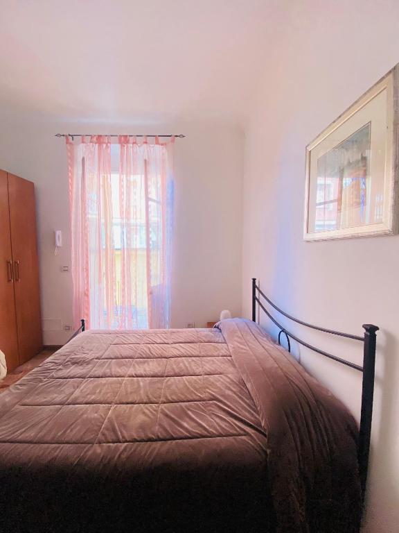 a bedroom with a bed with a brown comforter and a window at Il Nido Al Mare ROOM by 5TR Apartments in Levanto