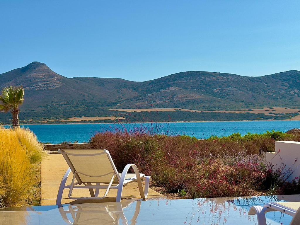 a chair sitting next to a body of water at Farous seaside sunset villa II in Andiparos