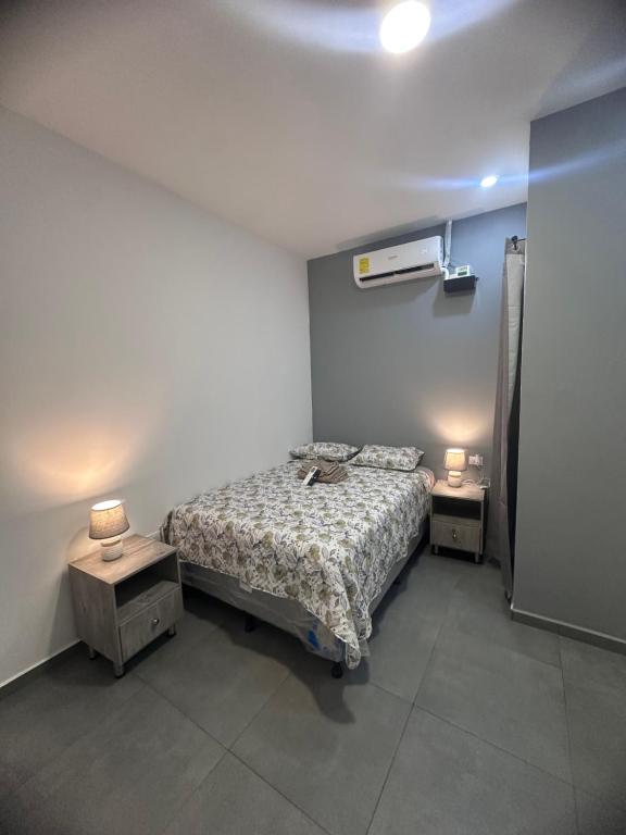 a bedroom with a bed and two night stands with lamps at Anturios House Apartamento 2 in San Marcos