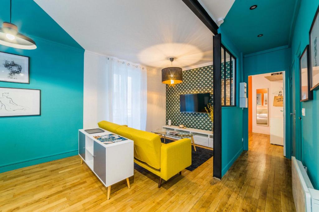a living room with a yellow couch and blue walls at L'Indigo - 1 Chambre in Brive-la-Gaillarde