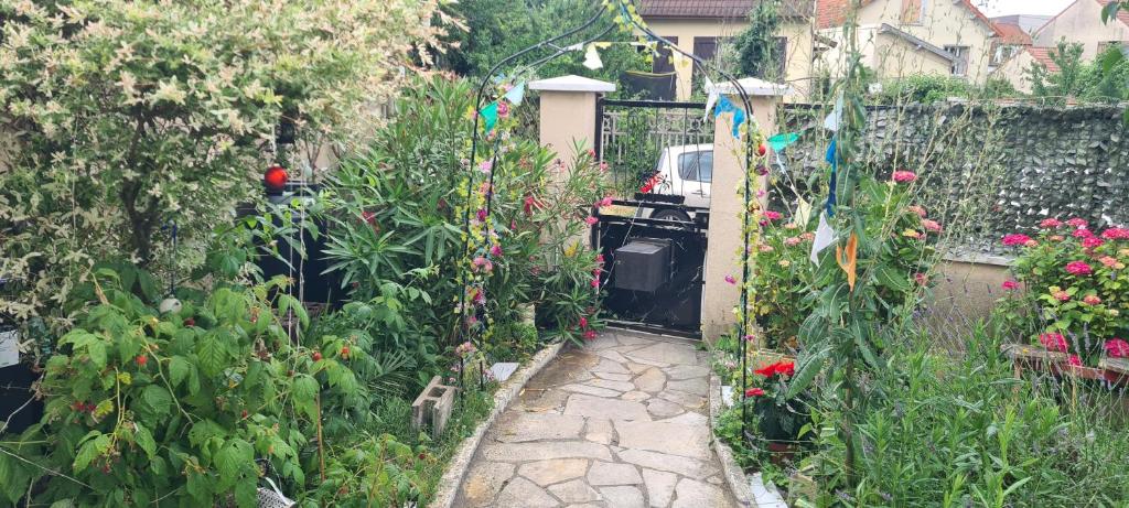 a garden with flowers and a stone walkway at KECYHOUSE chambre Légendes in Sevran