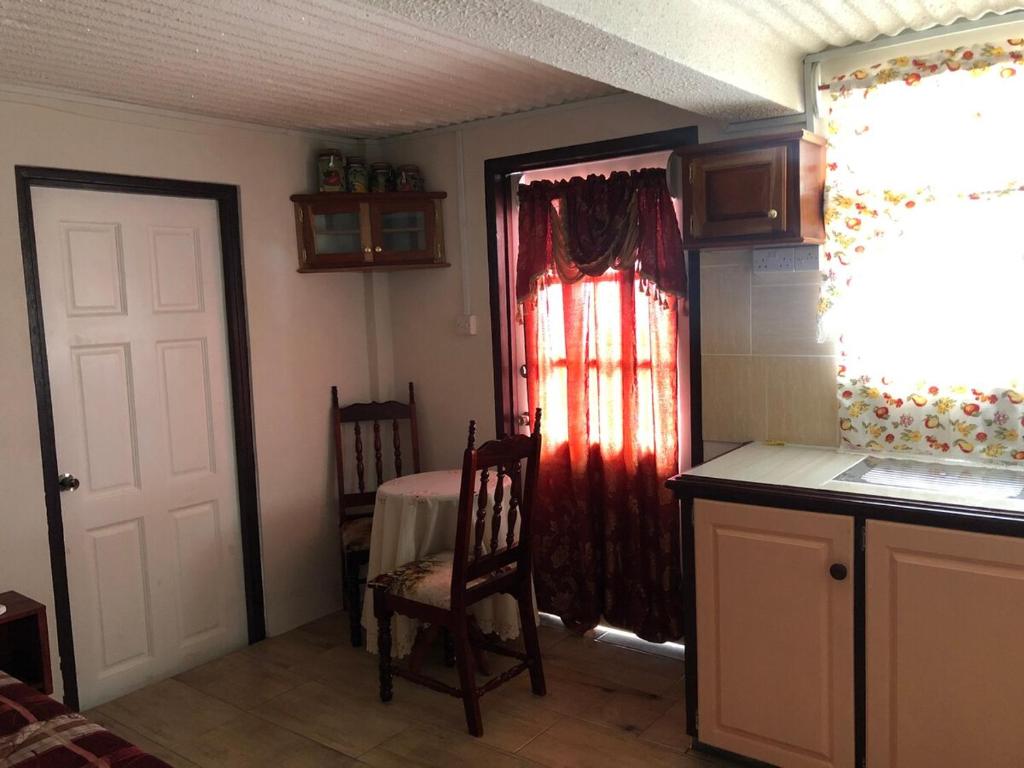 D View Cozy Corner في Gouyave: غرفة مع مطبخ مع طاولة وباب