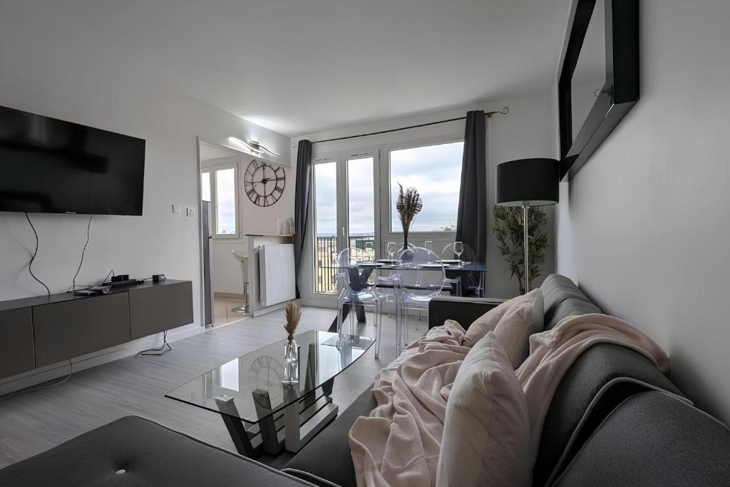 un salon avec un canapé et une table en verre dans l'établissement 3 pièces lumineux, balcon & parking - Paris 20 min, à Sartrouville