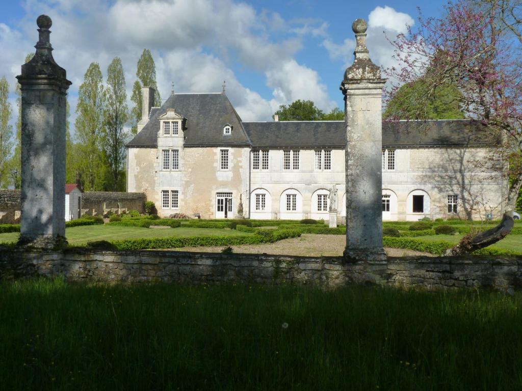 a large white house with a stone fence in front of it at LOGIS du Château du Bois Doucet in Bignoux