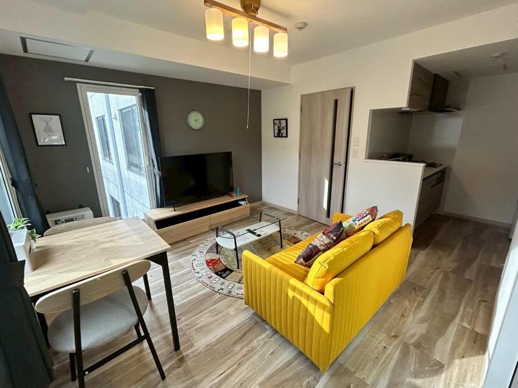 a living room with a yellow couch and a table at Satisfy サティスファイ in Chitose