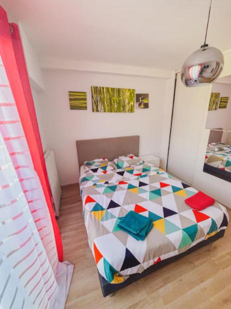 une chambre avec un lit avec une couette colorée dans l'établissement La ContrEscarpe - Studios fonctionnels - Secteur GARE CENTRE, à Amiens