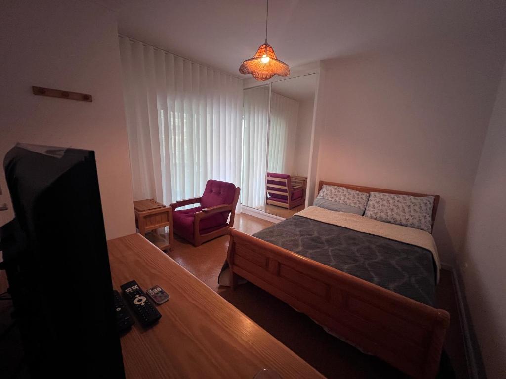 a small bedroom with a bed and a chair at Suíte-Refúgio á Beira-Mar Apartamento Partilhado in Viana do Castelo