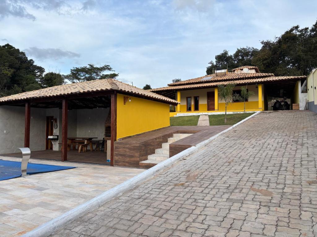 a yellow house with a pavilion and a patio at Casa Família in Brumadinho