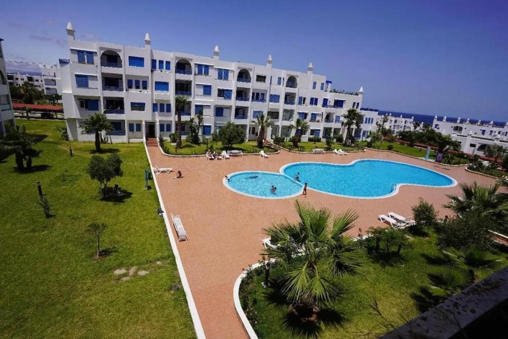 eine Luftansicht auf ein großes Gebäude mit zwei Swimmingpools in der Unterkunft 213 mdiq Appartement parfait à louer à kabila vista 2 chambre salon piscine 2 balcon 90 mètres carré in Marina Smir
