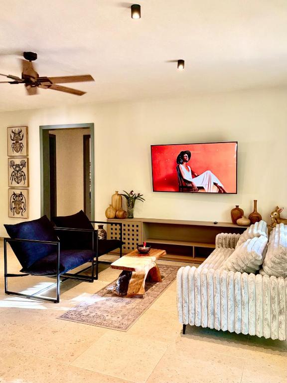een woonkamer met een bank en een tv aan de muur bij La Cueva De Piedra in Puerto Morelos