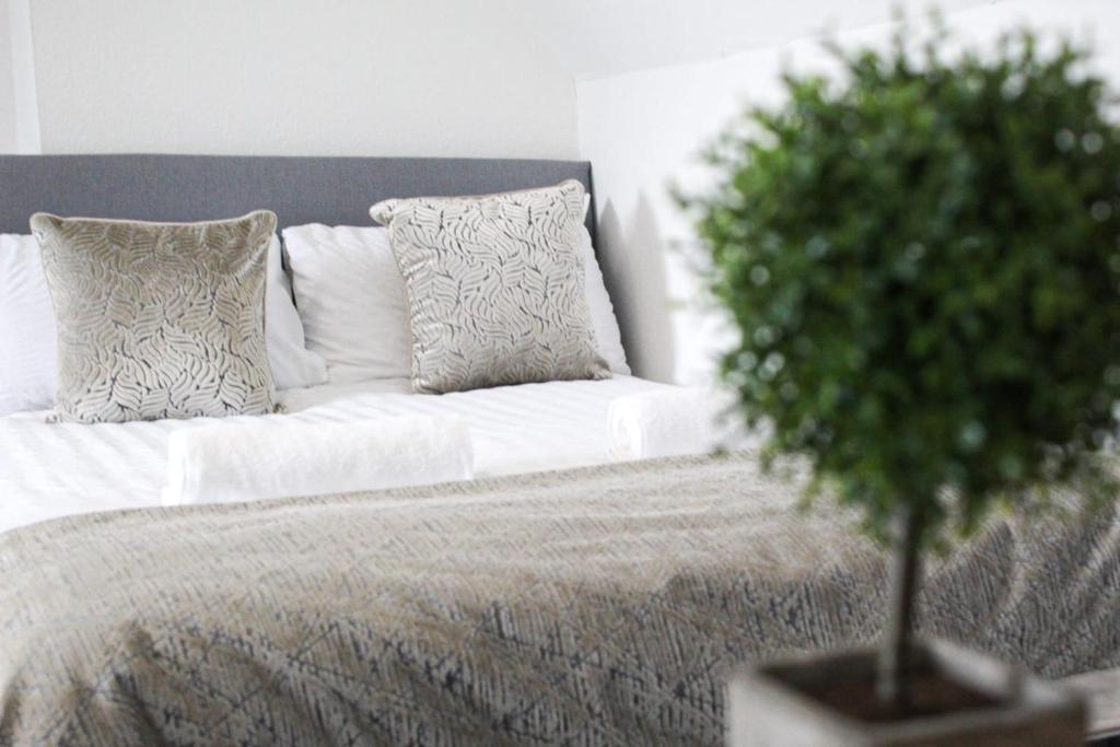 a white bed with pillows and a green plant on it at SHM Stays Solihull HS2 NEC Airport Nr M6 M40 M42 Great for Long & Short stays 15 min walk to Train Station 5 min drive to Town Centre outside Bus Stops & Supermarket Free Parking in Solihull