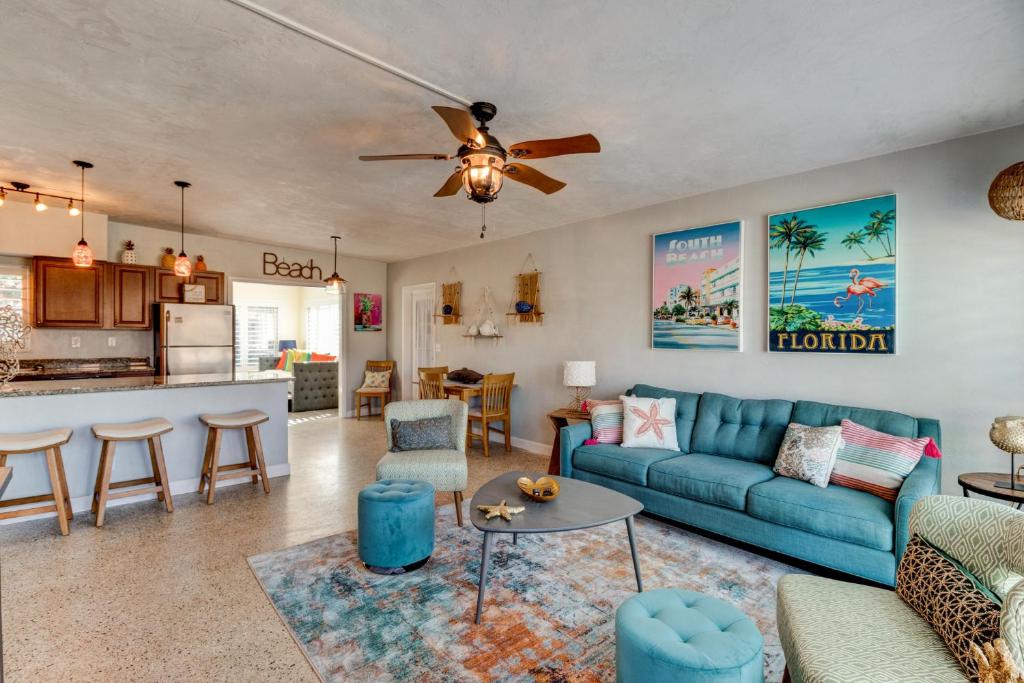 Una sala de estar con un sofá azul y una cocina. en Blowfish Bungalow-Cowboy Pool FirePit Ping Pong, en Daytona Beach