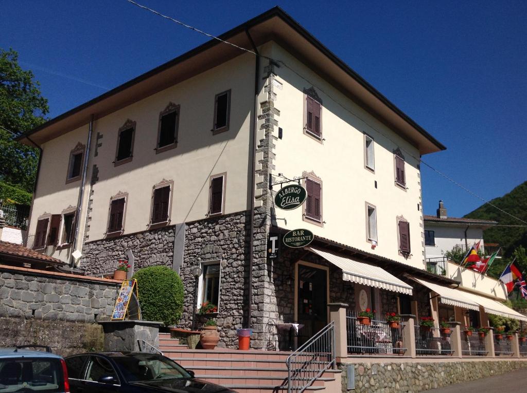 un grande edificio bianco con scale di fronte di Albergo Elisa a Comano