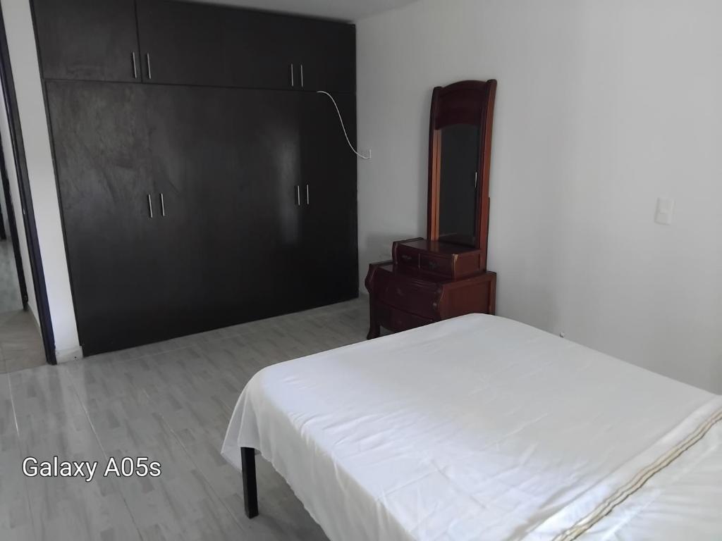 a bedroom with a white bed and a black cabinet at Villa kari in Palestina