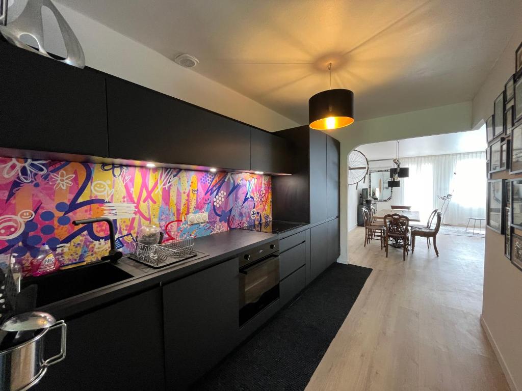 une cuisine avec des armoires noires et un mur coloré dans l'établissement Charmant 2 pièces à Sète avec balcon et climatisation - FR-1-338-625, à Sète