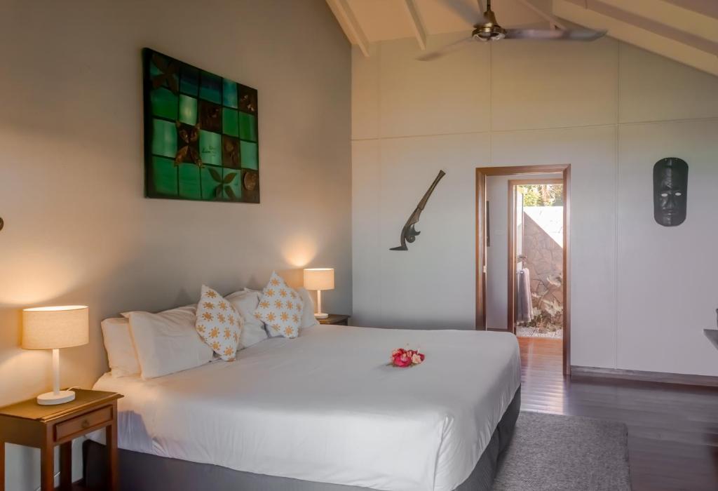 una camera da letto con un grande letto bianco con due lampade di Aroha Taveuni Beachfront Bures a Waiyevo