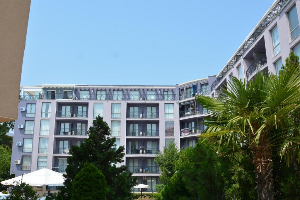 an apartment building with palm trees in front of it at Hotel Rainbow 3 Resort Club in Sunny Beach