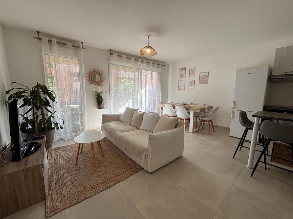 un salon avec un canapé blanc et une table dans l'établissement Cozy cocoon 2-bedroom apartment, à Agde