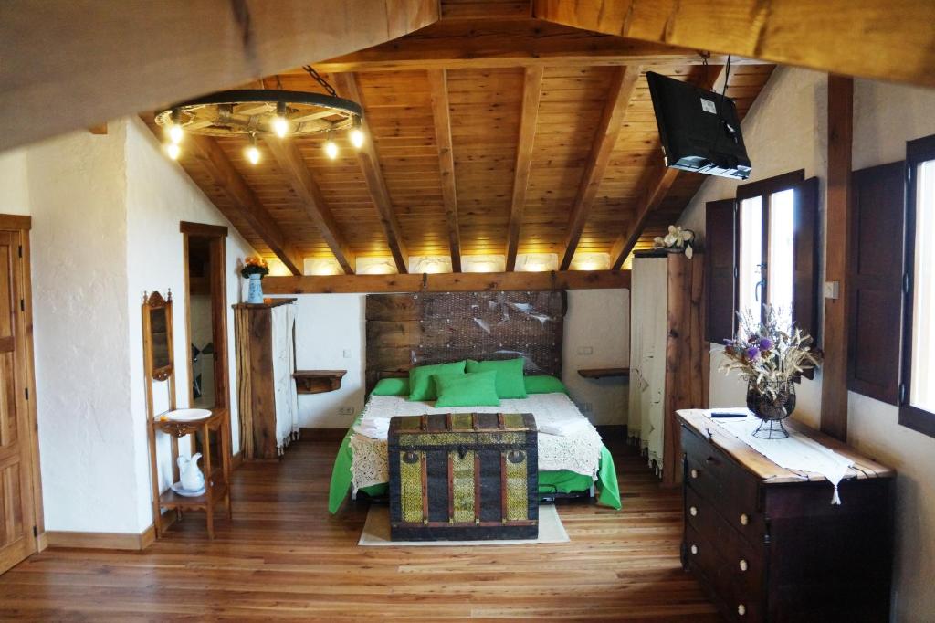 Un dormitorio con una cama con almohadas verdes. en Casa Rural Bioenergética La Serrezuela en Olmos de Atapuerca