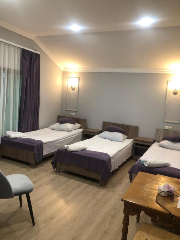 una camera d'albergo con tre letti e un tavolo di Guest House Anahit Ijevan a Ijevan