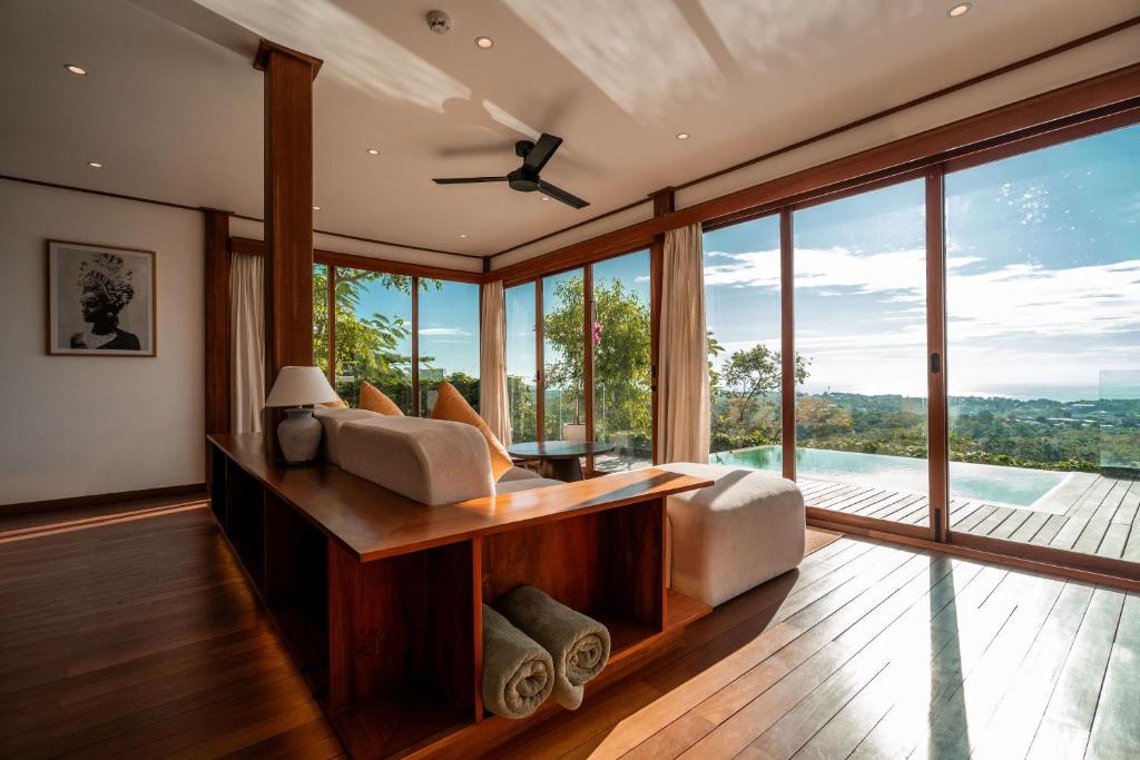 a bedroom with a bed and large glass windows at Grün Resort Uluwatu in Uluwatu
