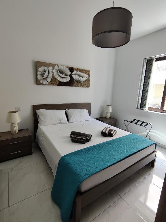 a bedroom with a bed with a blue blanket on it at Modern 2BR Apartment - Close to Gozo Ferry in Għajnsielem