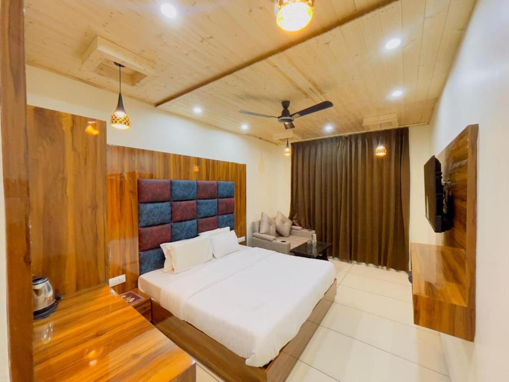 ダルハウジにあるHotel Dalhousie Hillsの白いベッドとテレビのある寝室