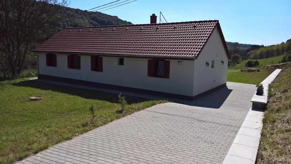 una pequeña casa blanca en una colina con entrada en Beppe Vendégház, en Abaliget
