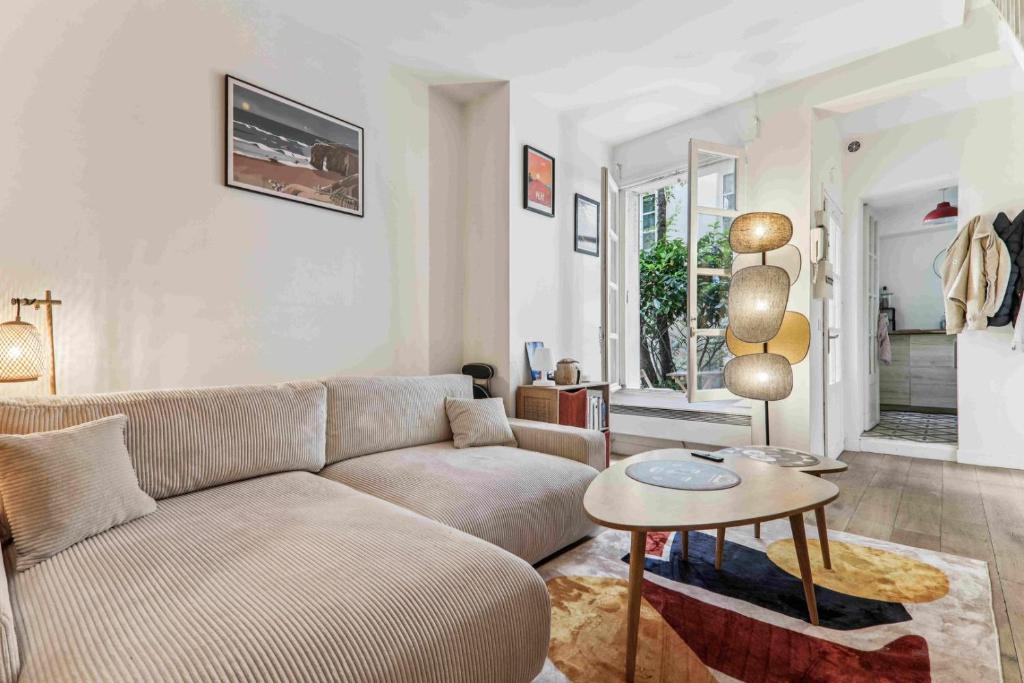 un salon avec un canapé et une table dans l'établissement Le Malicieux, à Paris