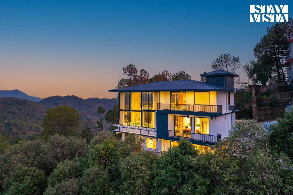 a house on a hill with lights on at StayVista at Petal Perch 4 BR and 2 BR with Bonfire in Kasauli in Kasauli
