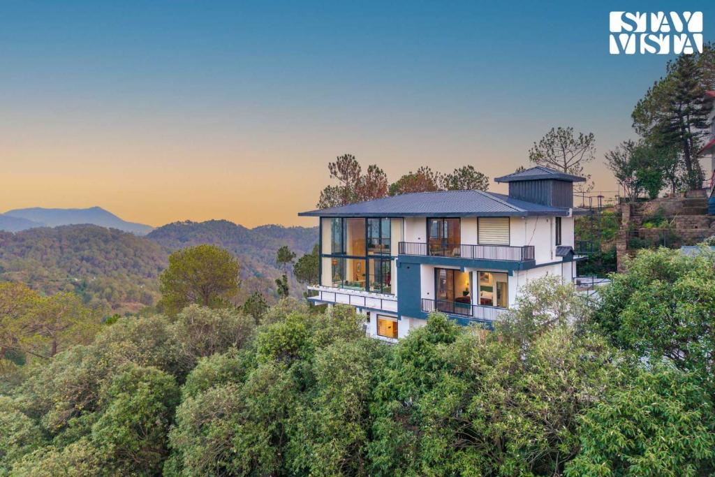 卡绍利StayVista at Petal Perch 4 BR with Bonfire, Gazebo in Kasauli的山顶上有树的房子