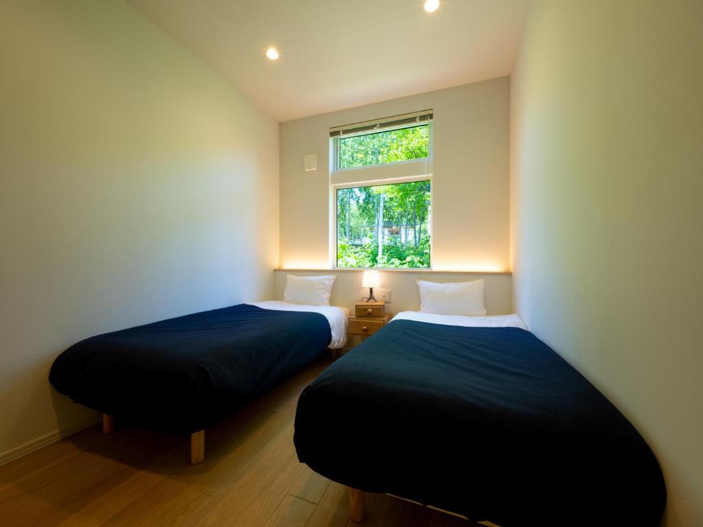 two beds in a room with a window at Minn house Niseko Hirafu in Kutchan