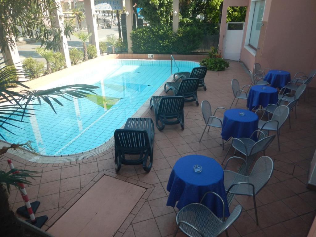 a pool with blue tables and chairs next to a swimming pool at Lake Hotel Ifigenia in Nago-Torbole