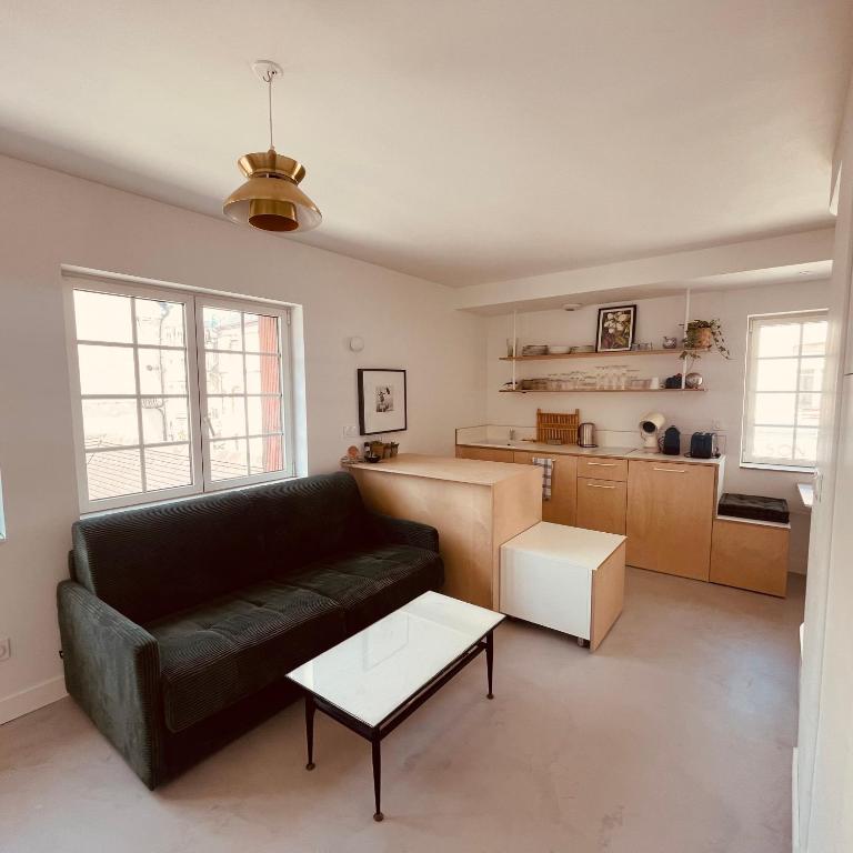 un salon avec un canapé noir et une cuisine dans l'établissement Studio Dizy, à Villers-sur-Mer