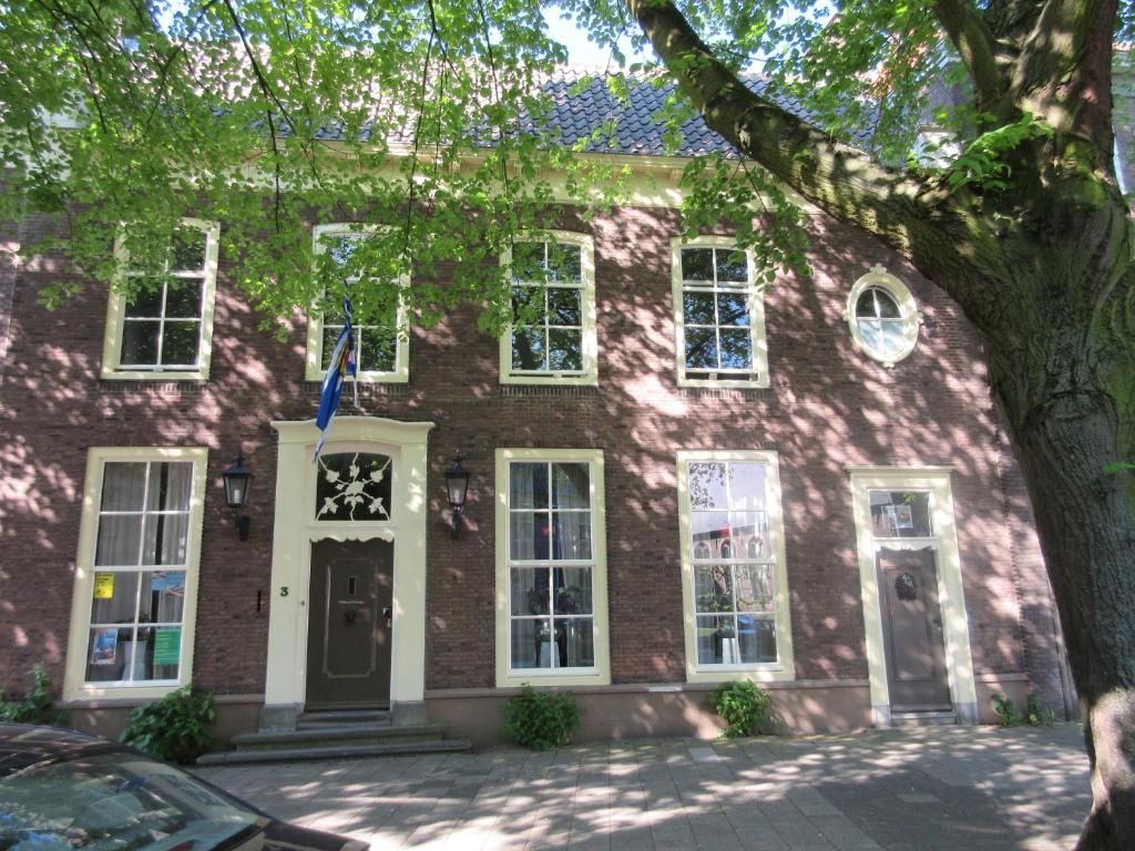 une maison en briques rouges avec des fenêtres blanches et un arbre dans l'établissement Guesthouse Groenmarkt, à Middelbourg