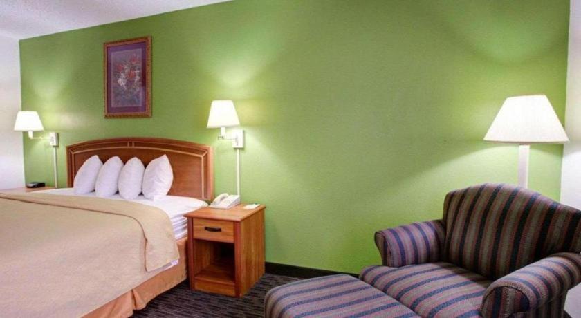 a hotel room with a bed and a chair at Quality Inn & Suites Airport in Austin
