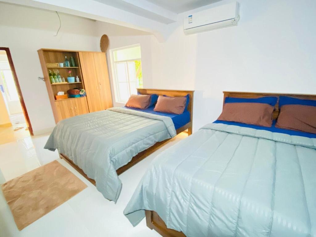 two beds in a room with white walls at Lima Blue Private Beach Apartment in Trincomalee